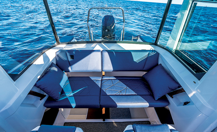 Overhead view of a blue seating area on the back of a white vessel out at sea.