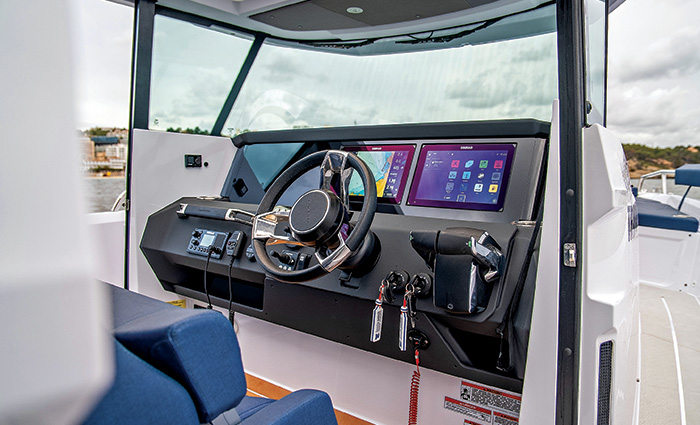 Black steering wheel and navigation system featuring dual monitors on a white boat.