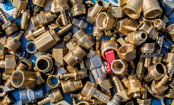 Numerous brass alloys spread out on a blue counter.