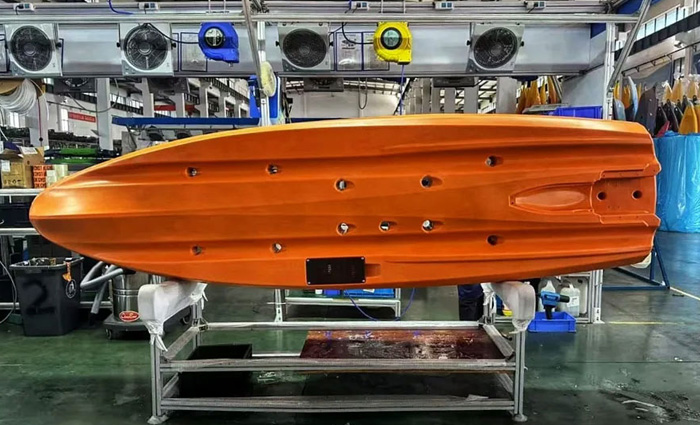 An orange jet drive propelled kayak on its side on showroom floor.