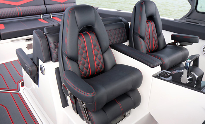 Two black bucket seats on a boat with additional red and black bench seating.