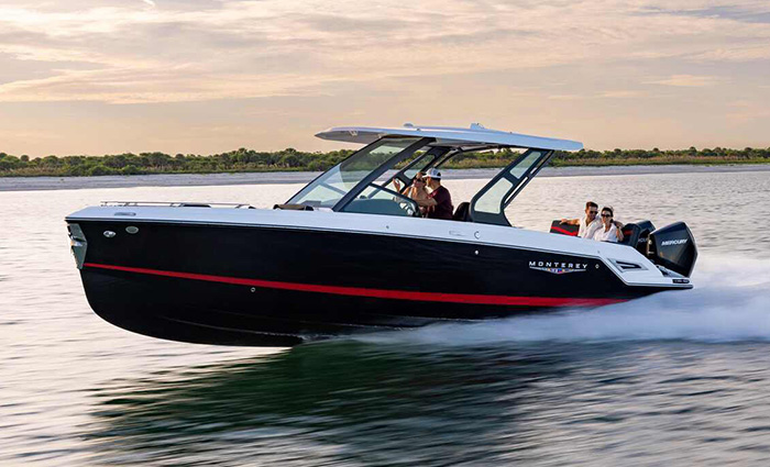Black, red and white sport boat speeding through a lake at sunset.