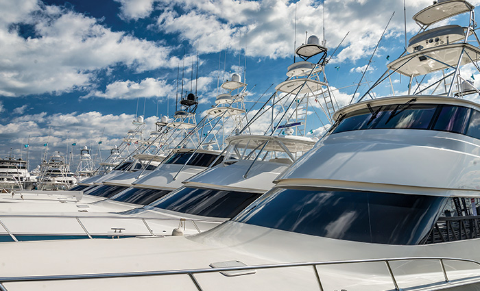 Row of white boats with large white clouds above on a sunny day.