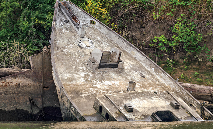 Abandoned, dirty and rusted boat shipwrecked on the shore.