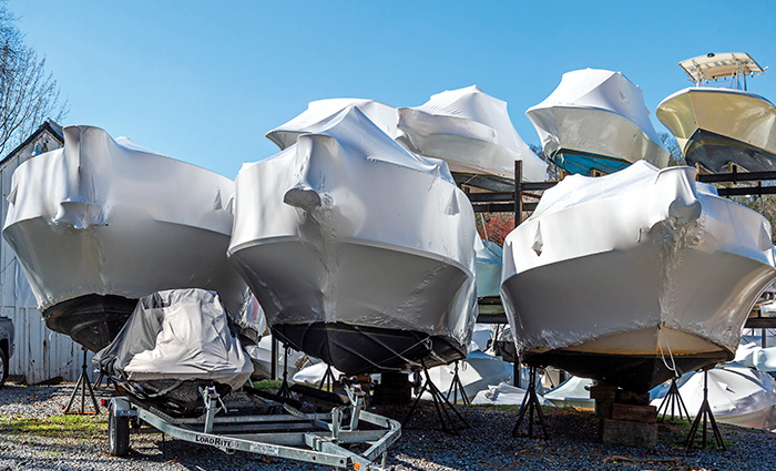 Eight boats stacked and in a line - seven with grey covers.