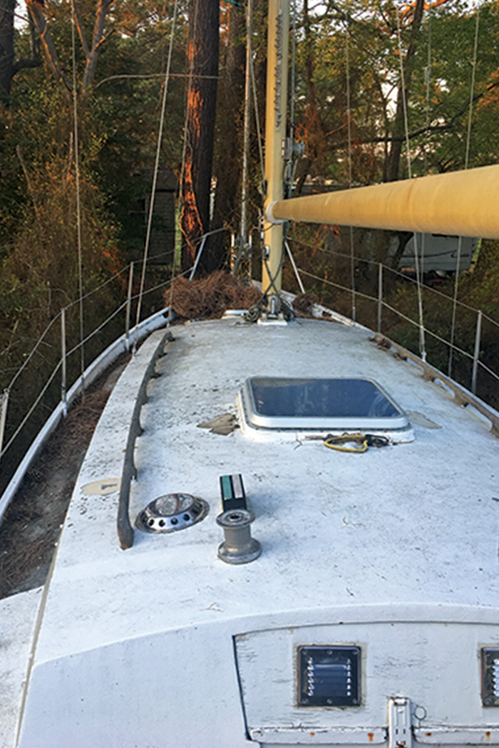 Top of an old and neglected white sailboat covered with dirt.