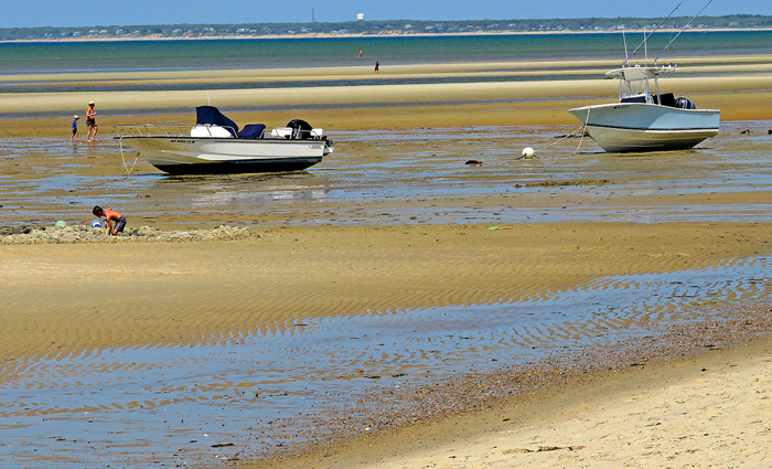 Two small fishing boats deserted on a beach during a sunny day.