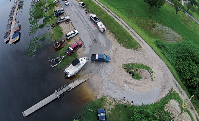 Aerial view of a marina including various multi-colored trucks launching boats into the water.