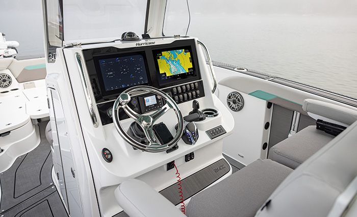 View of a a silver steering wheel and black navigation system on a white vessel.
