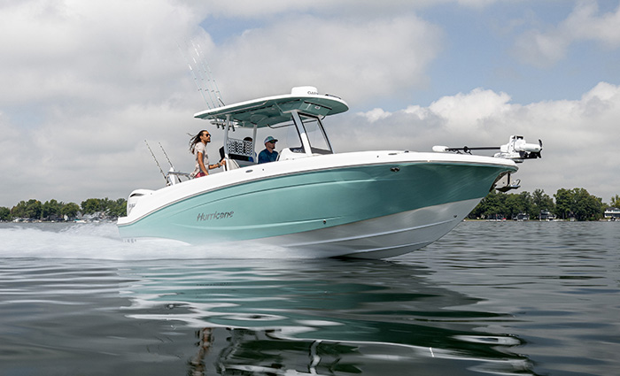 Three passengers aboard a teel blue and white vessel speeding through open waters on a cloudy day.