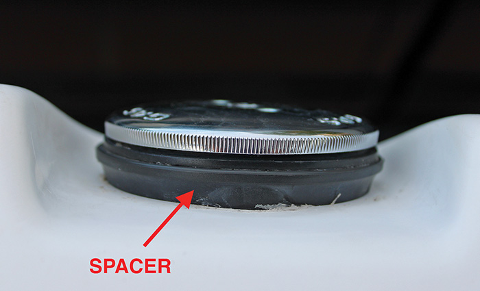 Up-close view of a fuel cap with red arrow pointing out the spacer.