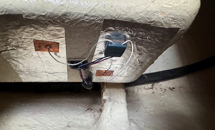 View from below of an exterior mounted navy blue sensor on a holding tank.