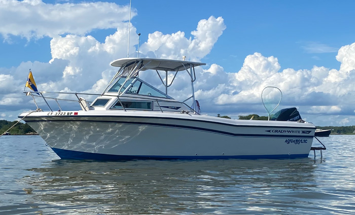 White boat anchored on the water with large white clouds in the background.