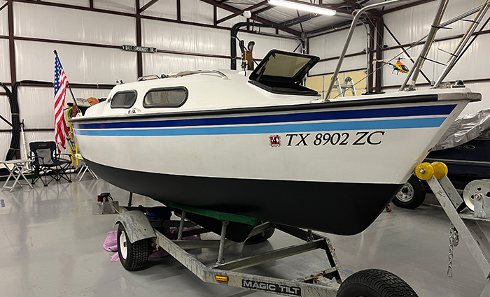 White boat with black trim and black lettering in a white garage.