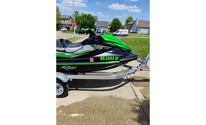 Black and green jet ski on a trailer in a driveway.